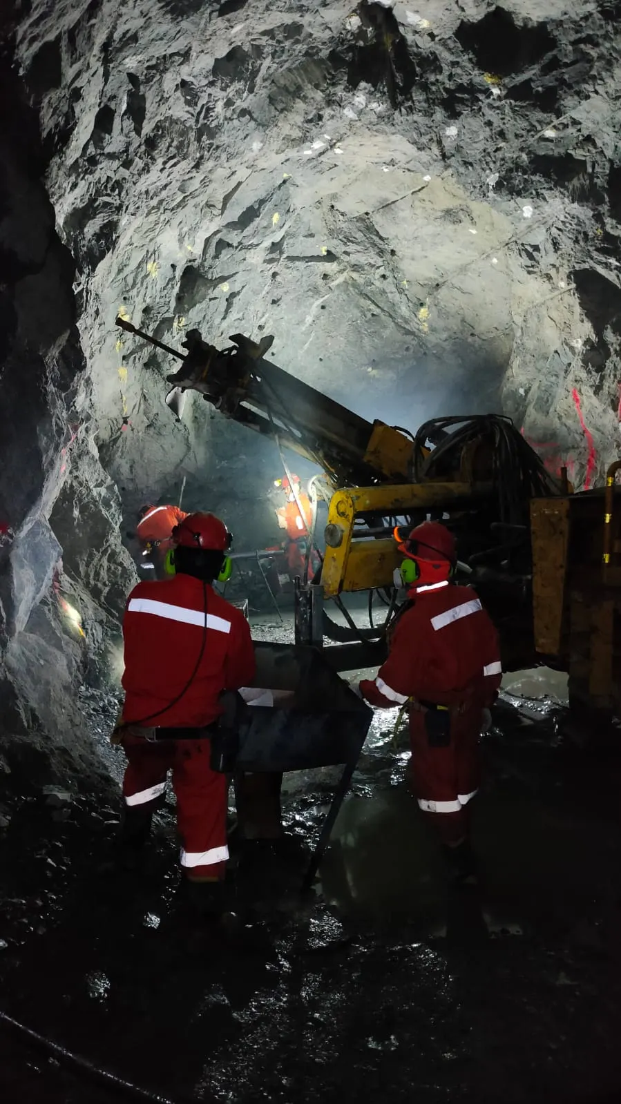 Mineros operando perforadora en túnel subterráneo