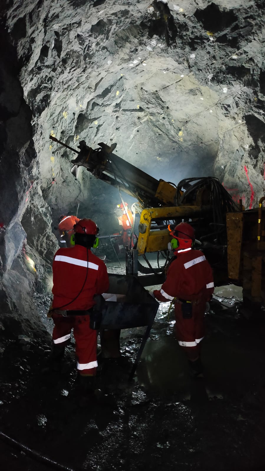 Mineros operando perforadora en túnel subterráneo